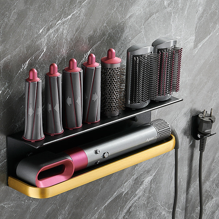 Set of hair styling tools including a hair dryer and brushes on a wall-mounted shelf against a gray marble wall.